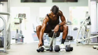 Athlete resting between sets in a gym, checking their watch to time recovery period