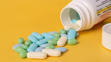 Mixed pills spilling out of a pill bottle.