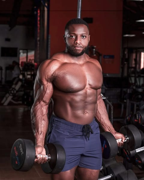 Gachau Njoroge posing shirtless holding dumbbells