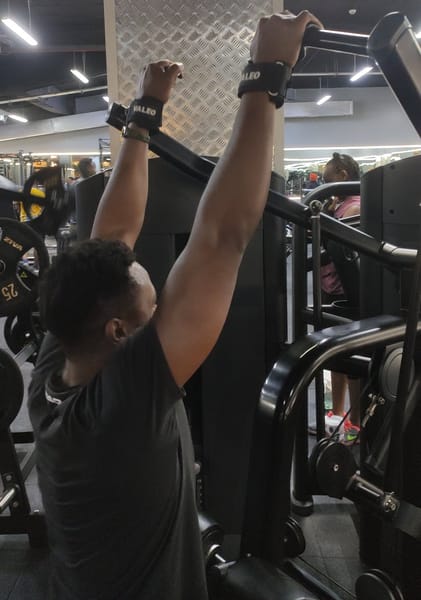 Athlete performing lat pulldown exercise using lifting hooks attached to cable machine handle
